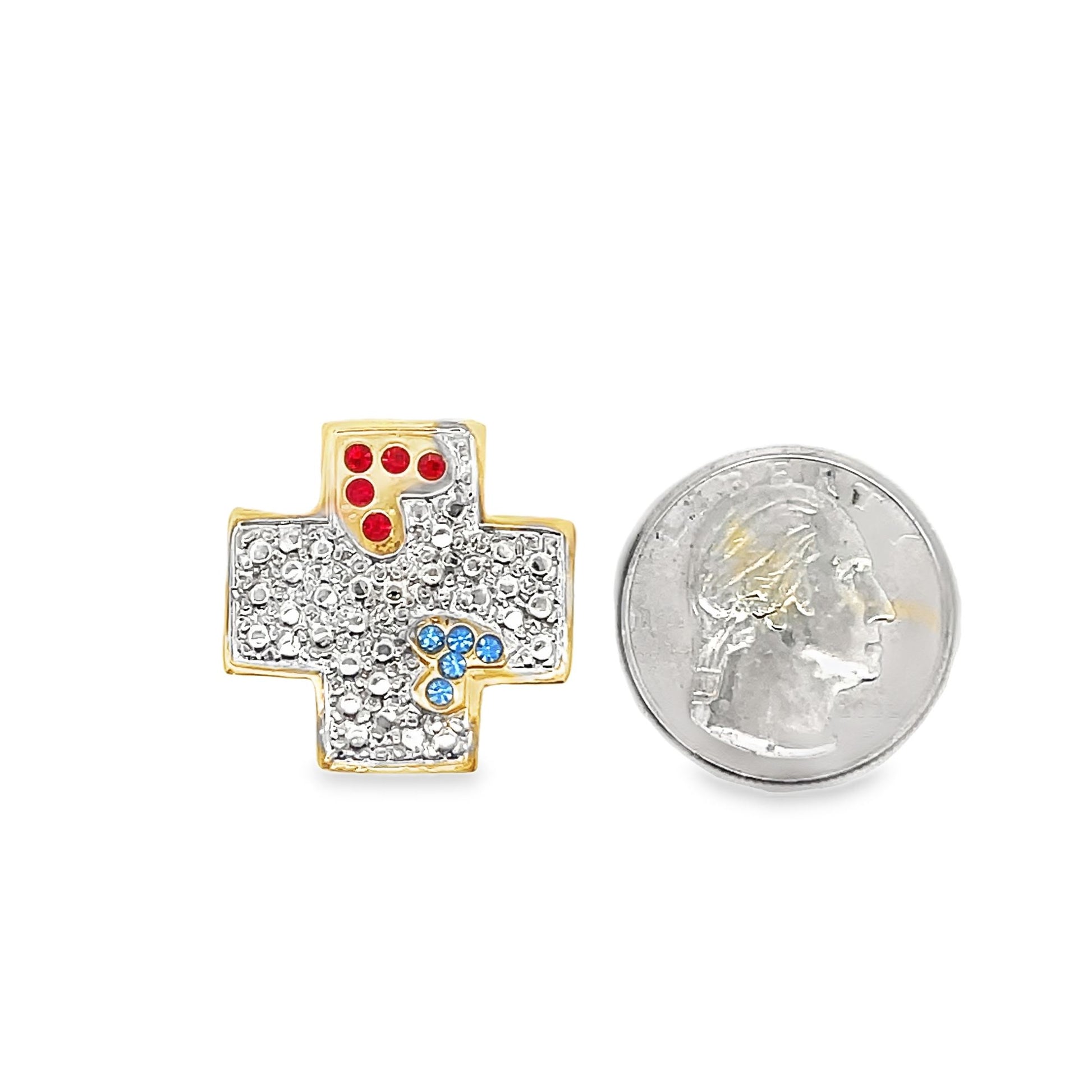A gold cross pendant encrusted with clear, red, and blue gemstones sits next to a US quarter coin for scale.
