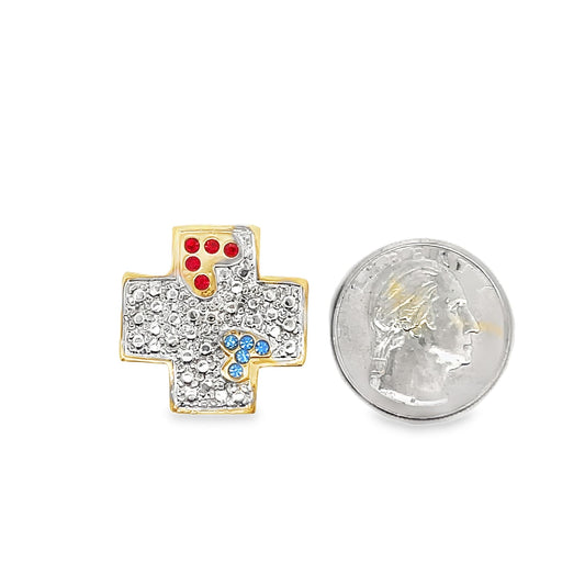 A gold cross pendant encrusted with clear, red, and blue gemstones sits next to a US quarter coin for scale.