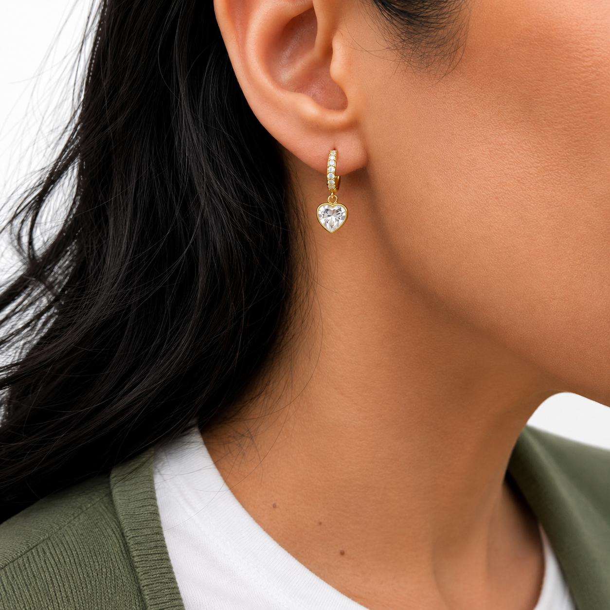 Elegant 18K Gold Filled pave huggie earrings featuring sparkling heart-cut CZ drop charms. Lightweight, hypoallergenic, tarnish resistant, and perfect for everyday wear or gifting.