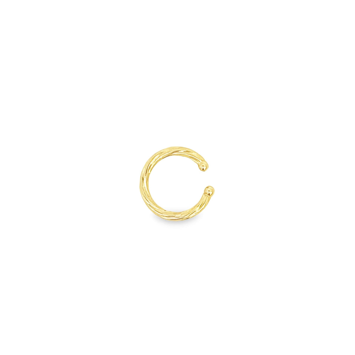 A textured gold ear cuff rests against a plain white background.