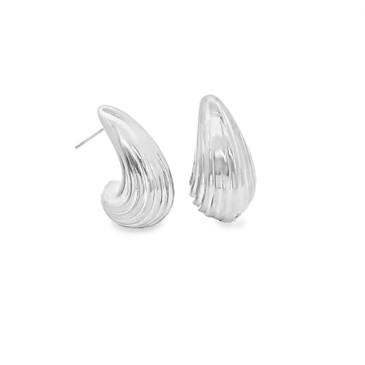 A pair of shiny silver dome earrings with a ridged seashell design rests against a clean white background.