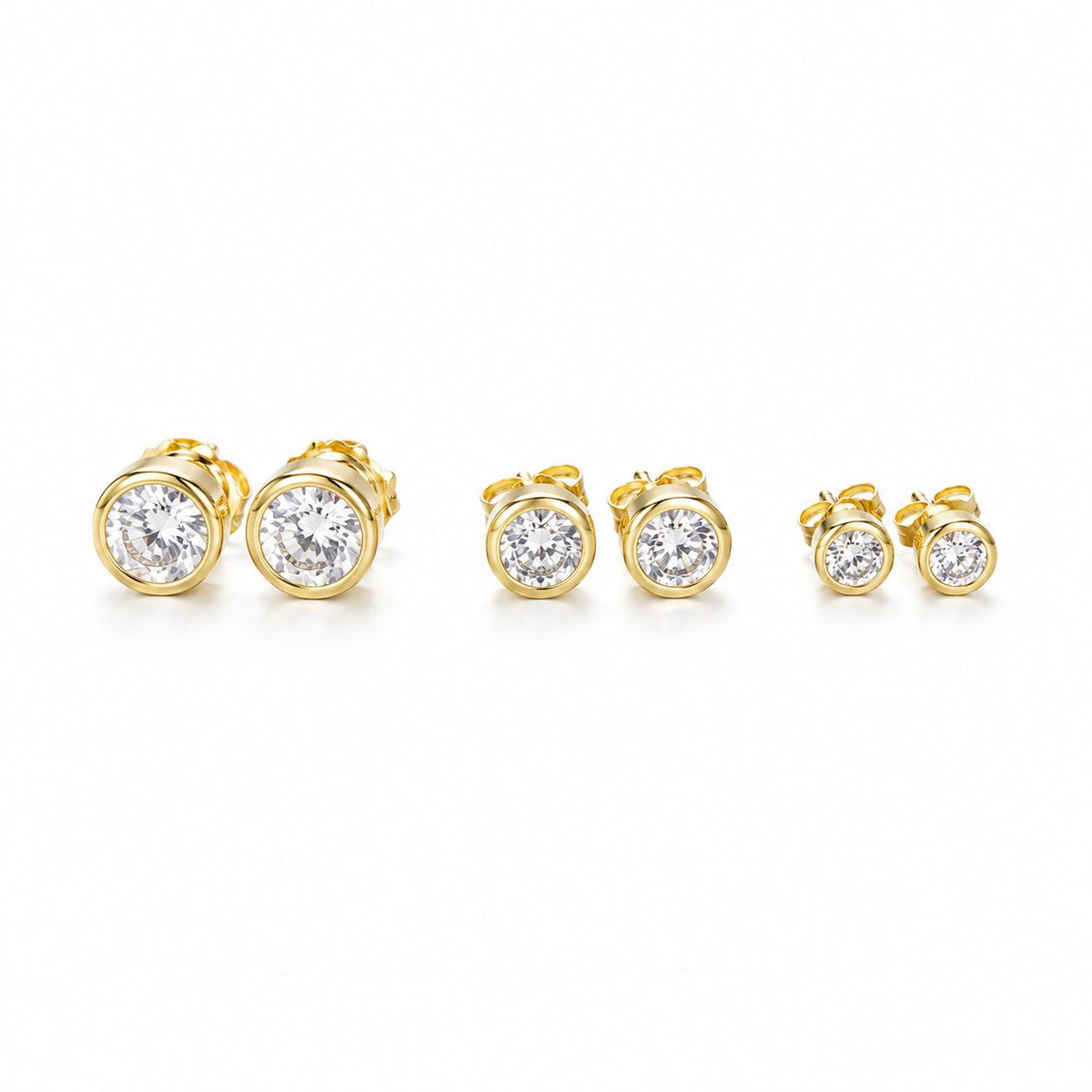 Three pairs of round bezel-set cubic zirconia gold stud earrings sit in graduating sizes on a white background.