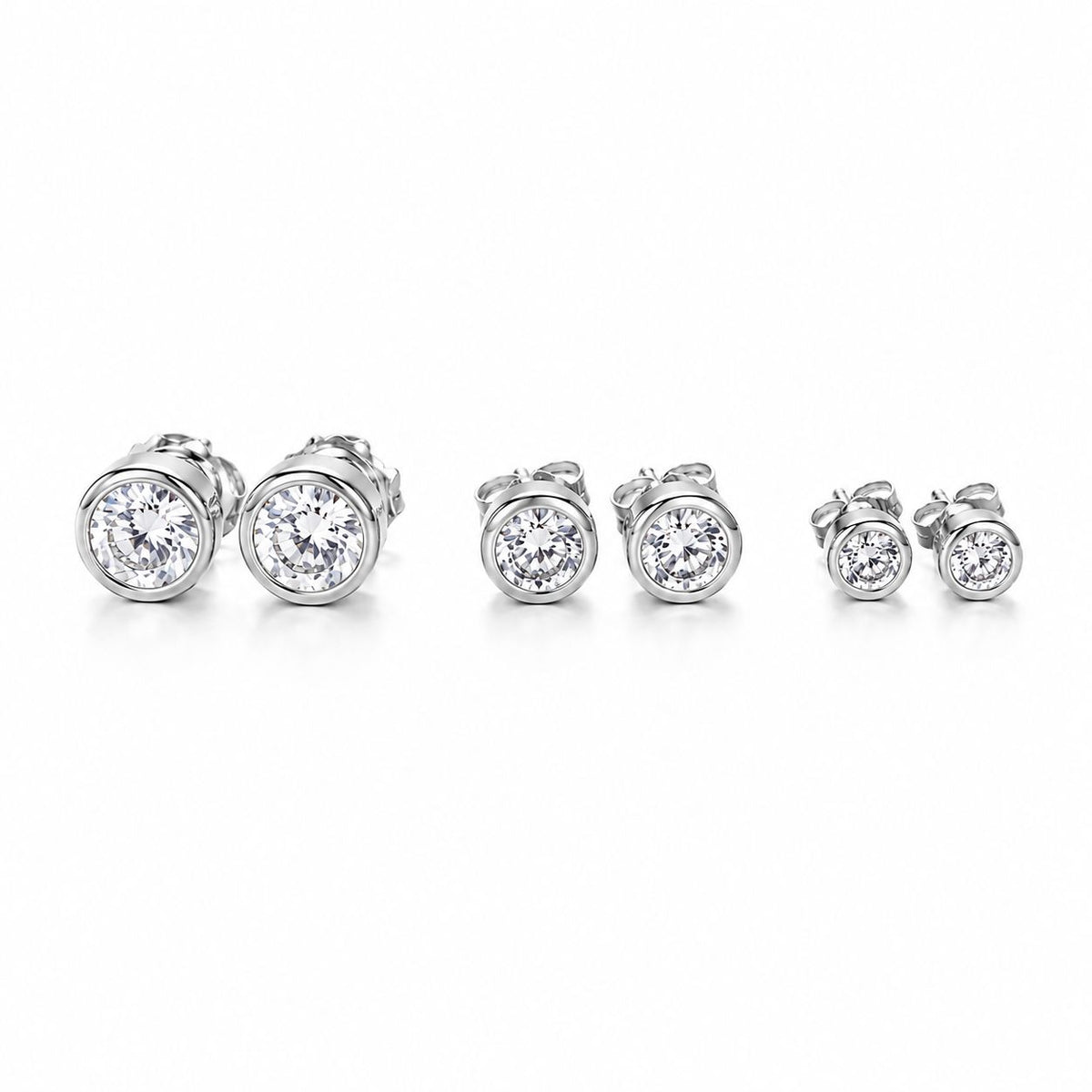 Three pairs of bezel-set round diamond stud earrings in descending sizes sit in a row on a white background.