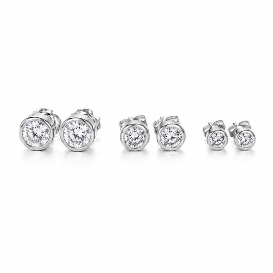 Three pairs of bezel-set round diamond stud earrings in descending sizes sit in a row on a white background.