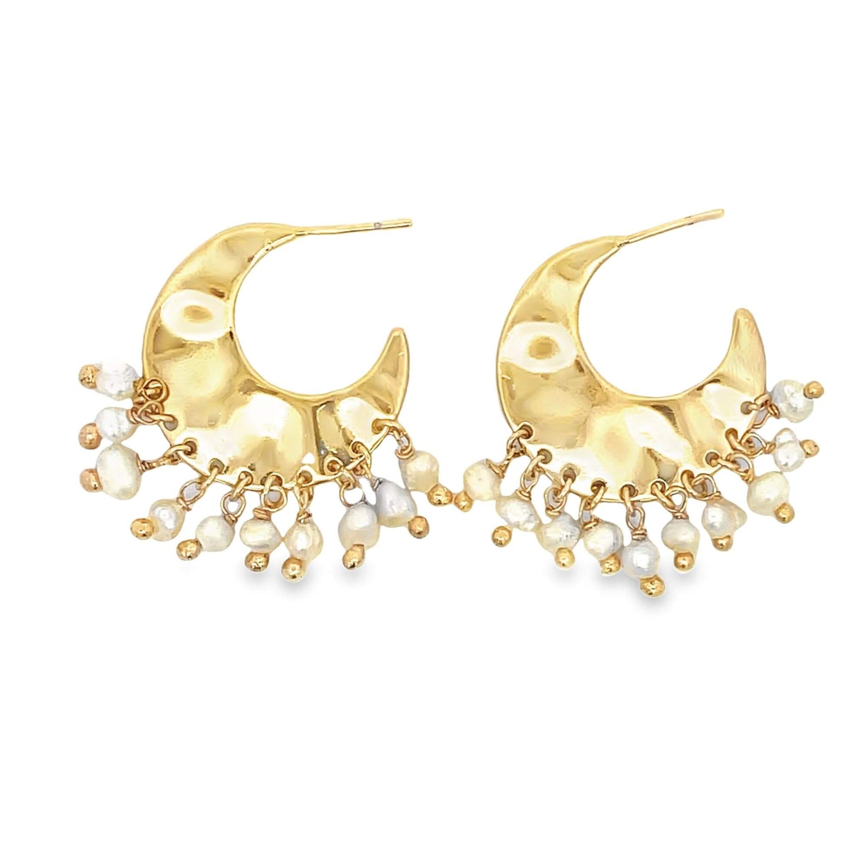 A pair of hammered gold crescent hoop earrings dangling delicate white pearls against a plain white background.