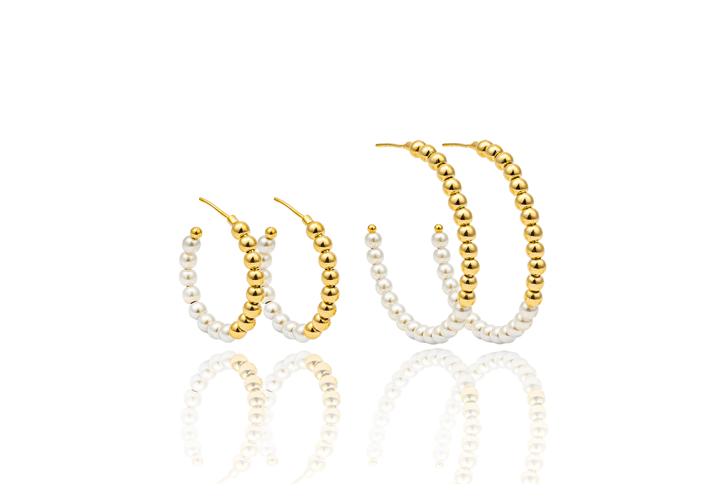 Two pairs of gold and pearl beaded hoop earrings display their reflective surfaces against a white background.