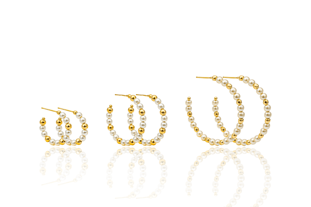 Three pairs of gold hoop earrings featuring alternating white pearls and gold beads display in ascending sizes against a white background.