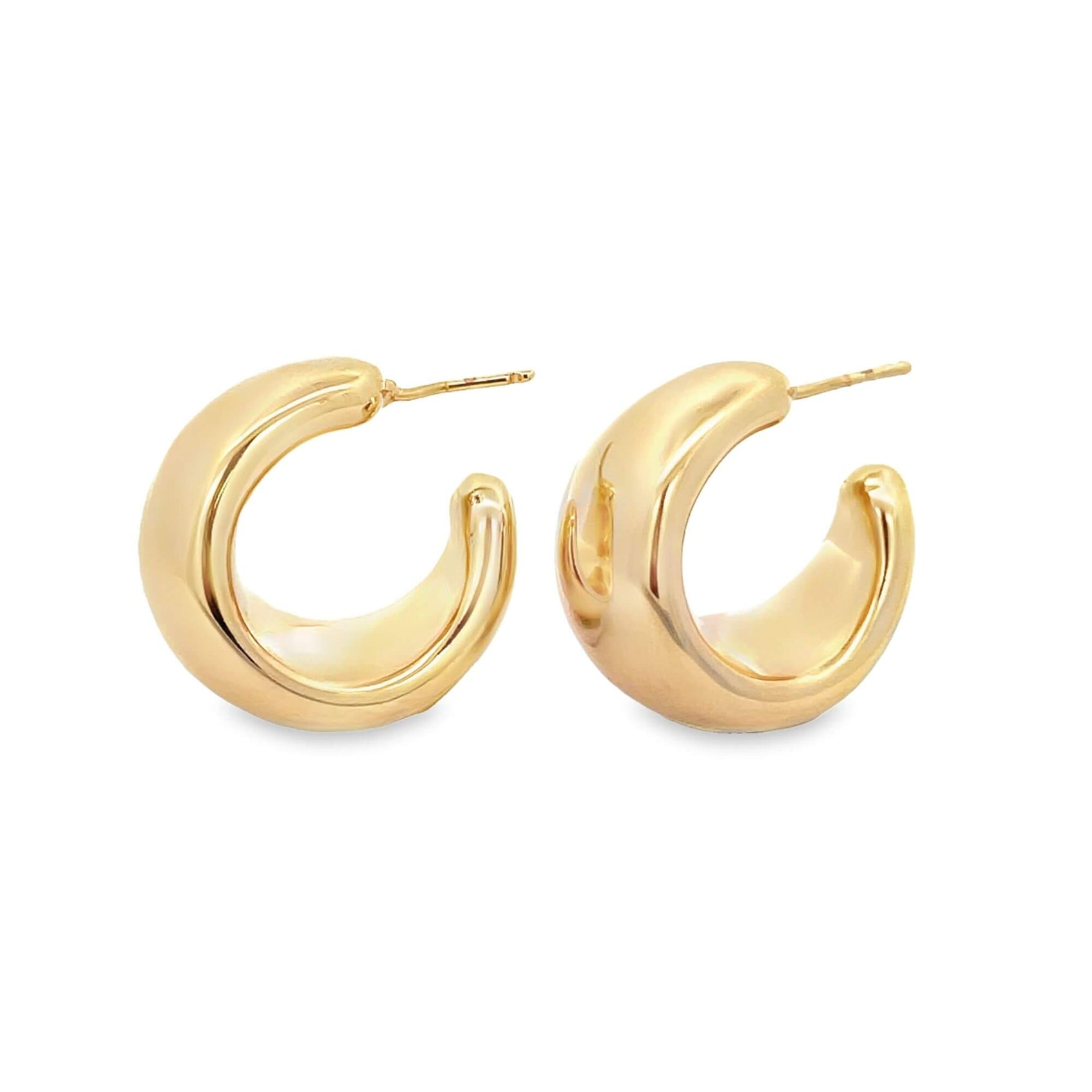 A pair of thick, polished gold huggie hoop earrings rests against a clean white background.