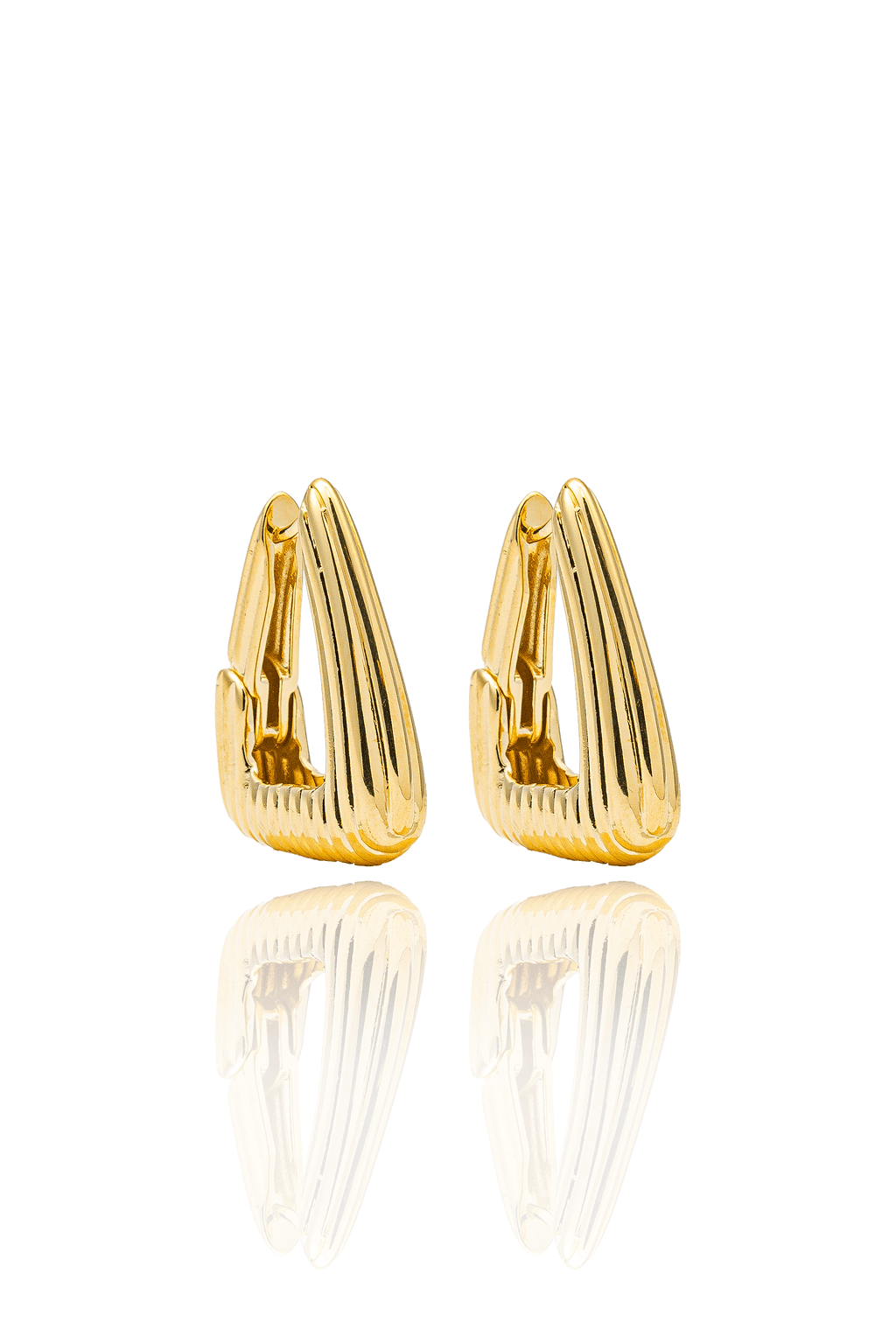 A pair of shiny gold triangular hoop earrings featuring ribbed texturing stand side-by-side on a reflective white surface.