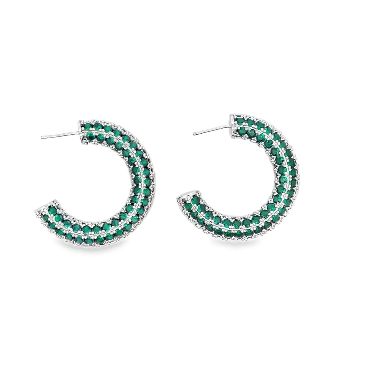 A pair of silver hoop earrings paved with sparkling green stones displays against a clean white background.
