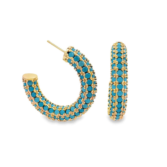 A pair of gold hoop earrings features vibrant turquoise gemstone beads embedded throughout the design against a white background.