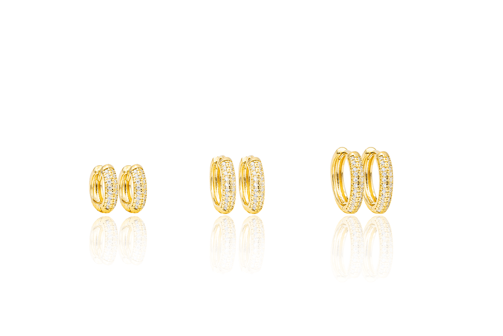 Three pairs of gold pave huggie hoop earrings display varying sizes against a clean white background with subtle reflections.
