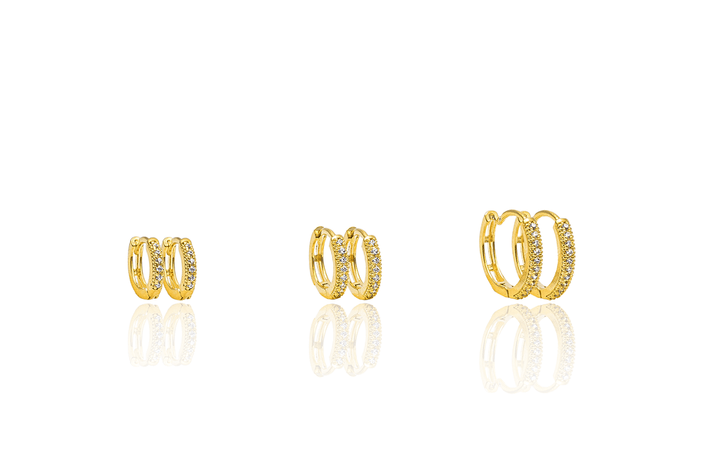 Three pairs of glittering gold huggie hoop earrings showcase a sparkling pave setting against a clean white background.