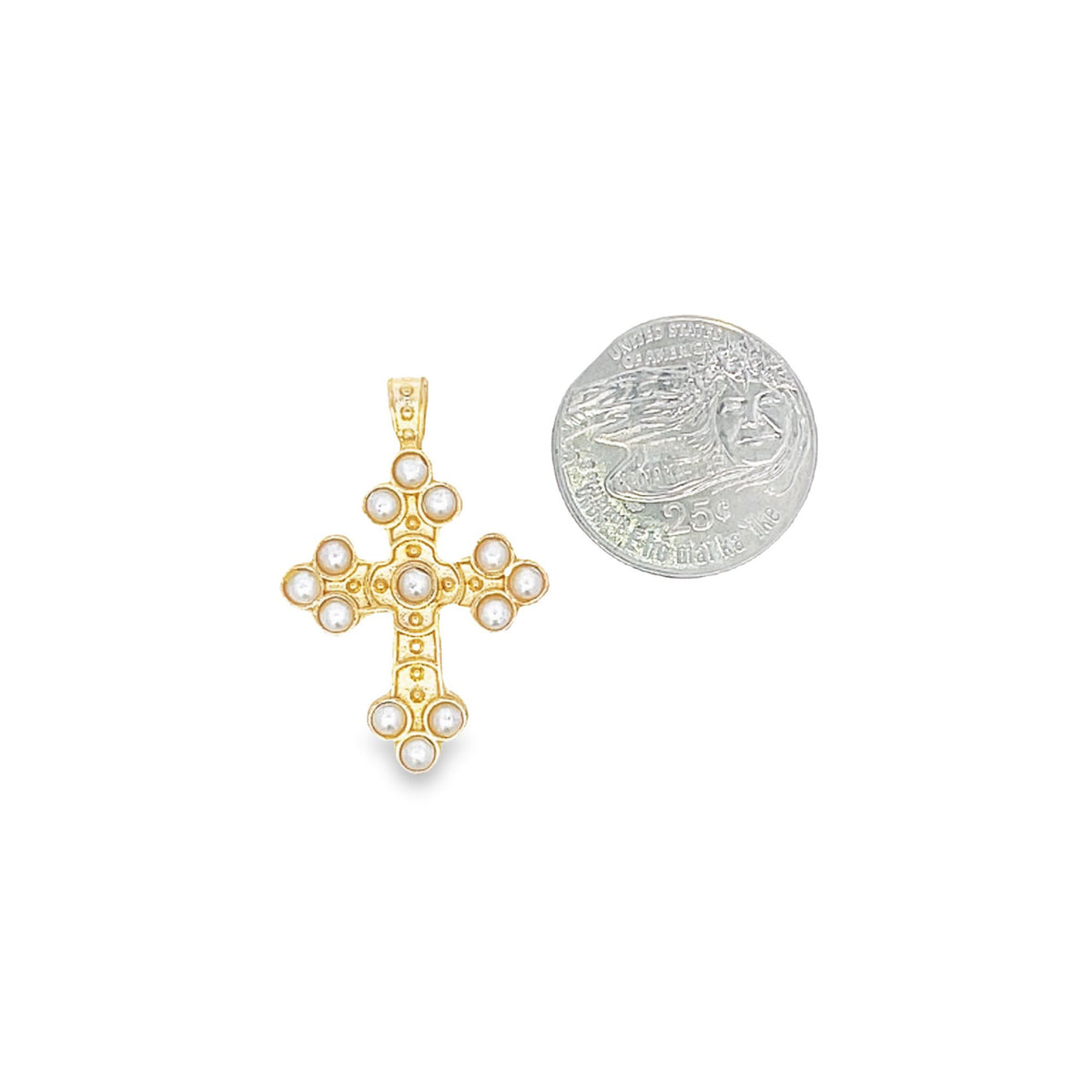 A gold cross pendant embedded with small pearls rests next to a quarter for scale on a white background.