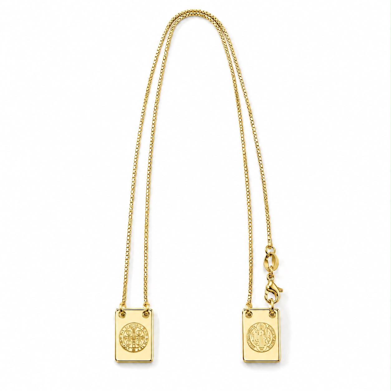A gold Saint Benedict scapular necklace features a delicate box chain connecting two rectangular medals against a plain white background.