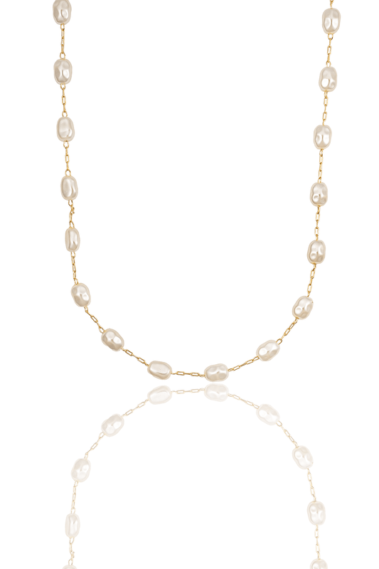 A delicate gold chain necklace features evenly spaced baroque pearls against a stark white background with a subtle reflection.