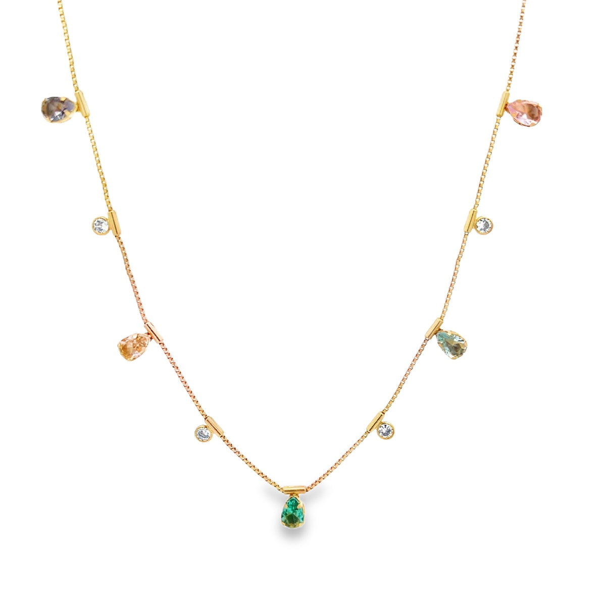 A delicate gold chain necklace dangles multicolored gemstone drops, featuring a central green emerald-cut pendant against a clean white background.