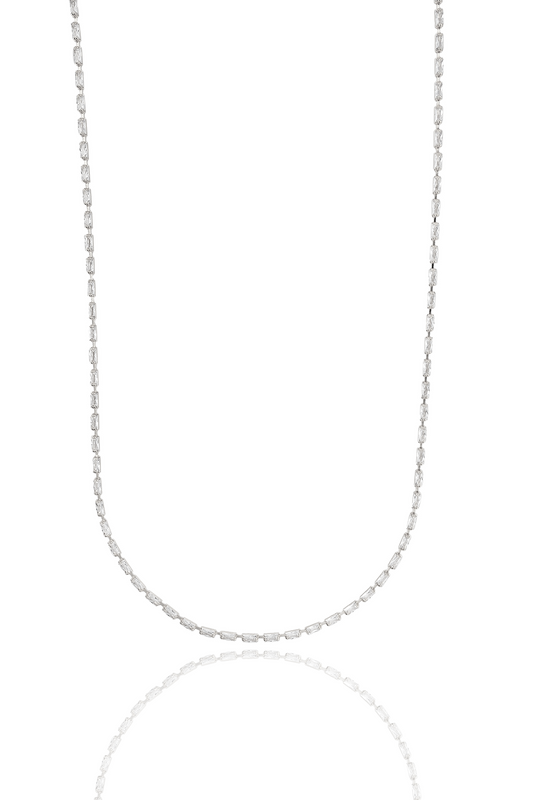 A delicate diamond baguette station necklace glimmers against a stark white background.