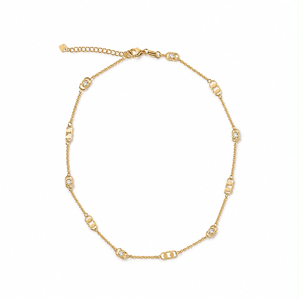 A delicate gold chain necklace sparkles against a plain white background, featuring alternating linked patterns and small crystal accents.