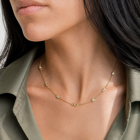 A model wears a delicate gold chain necklace with interspersed diamond accents.