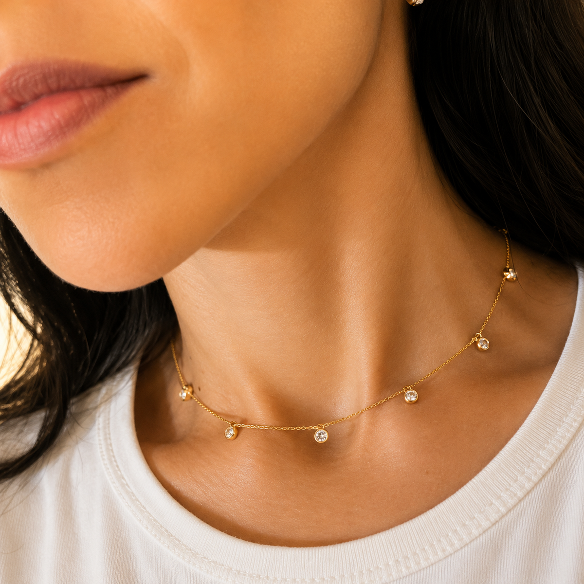 A woman wearing a delicate gold station necklace with scattered bezel-set diamonds around her neck.