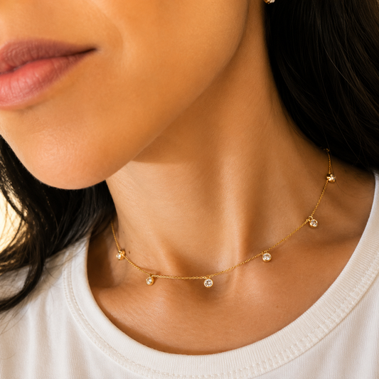 A woman wearing a delicate gold station necklace with scattered bezel-set diamonds around her neck.