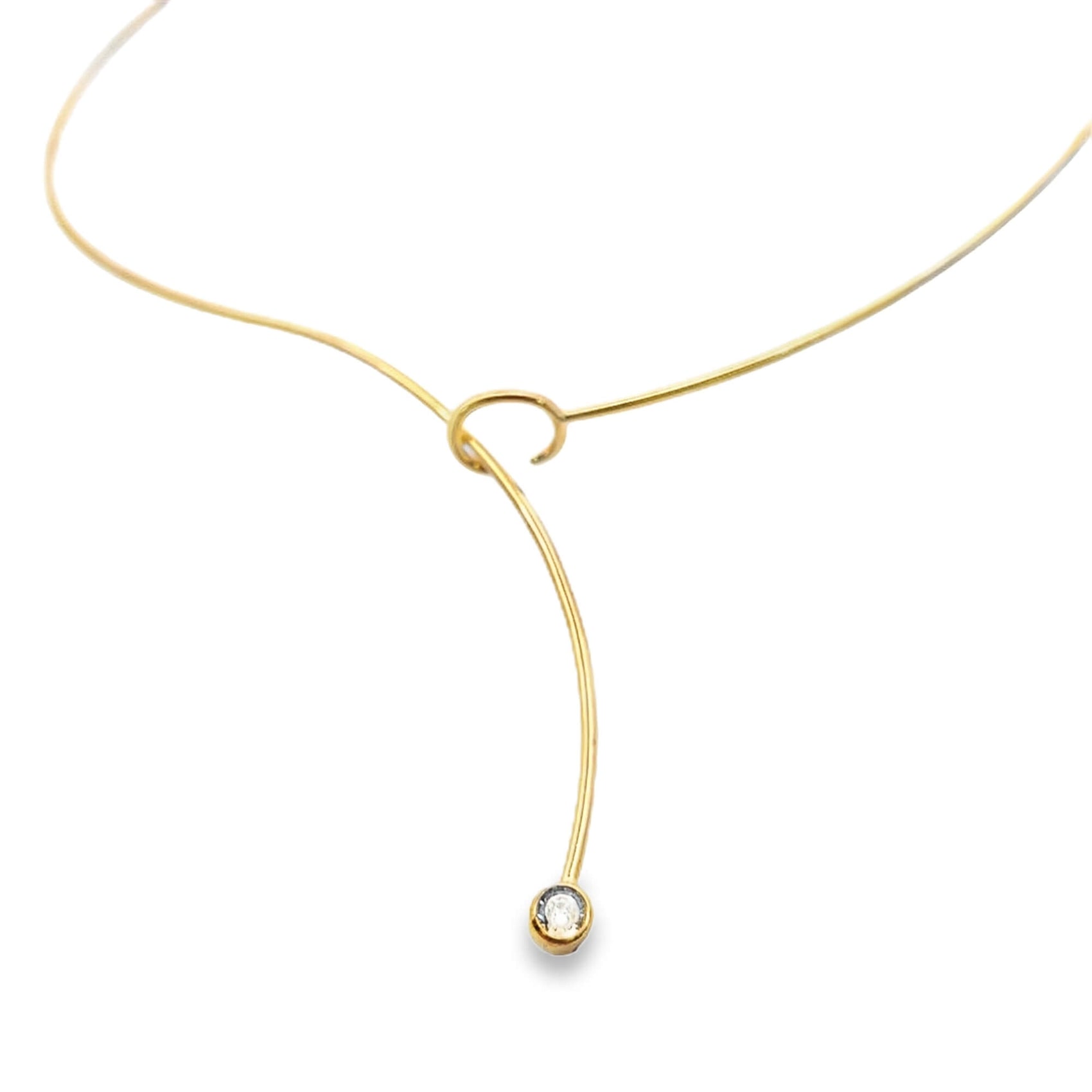 A delicate gold lariat necklace features a curved wire ending in a sparkling bezel-set diamond pendant against a clean white background.