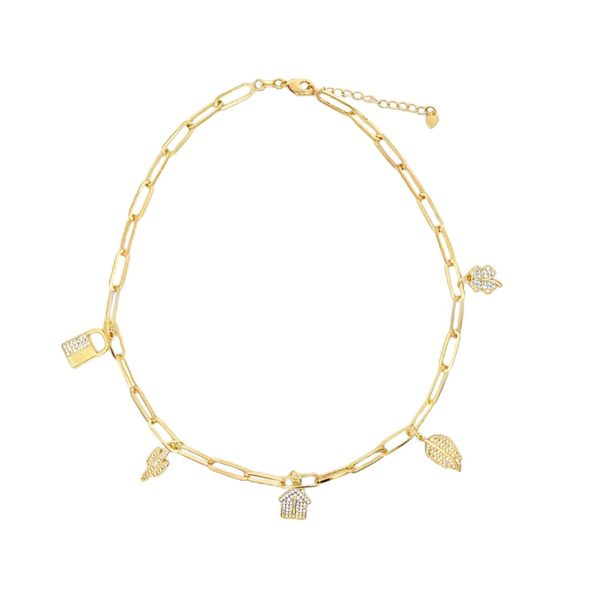 A gold paperclip chain necklace features dangling charms shaped like a house, lock, leaves, and a flower, all embellished with sparkling crystals against a clean white background.
