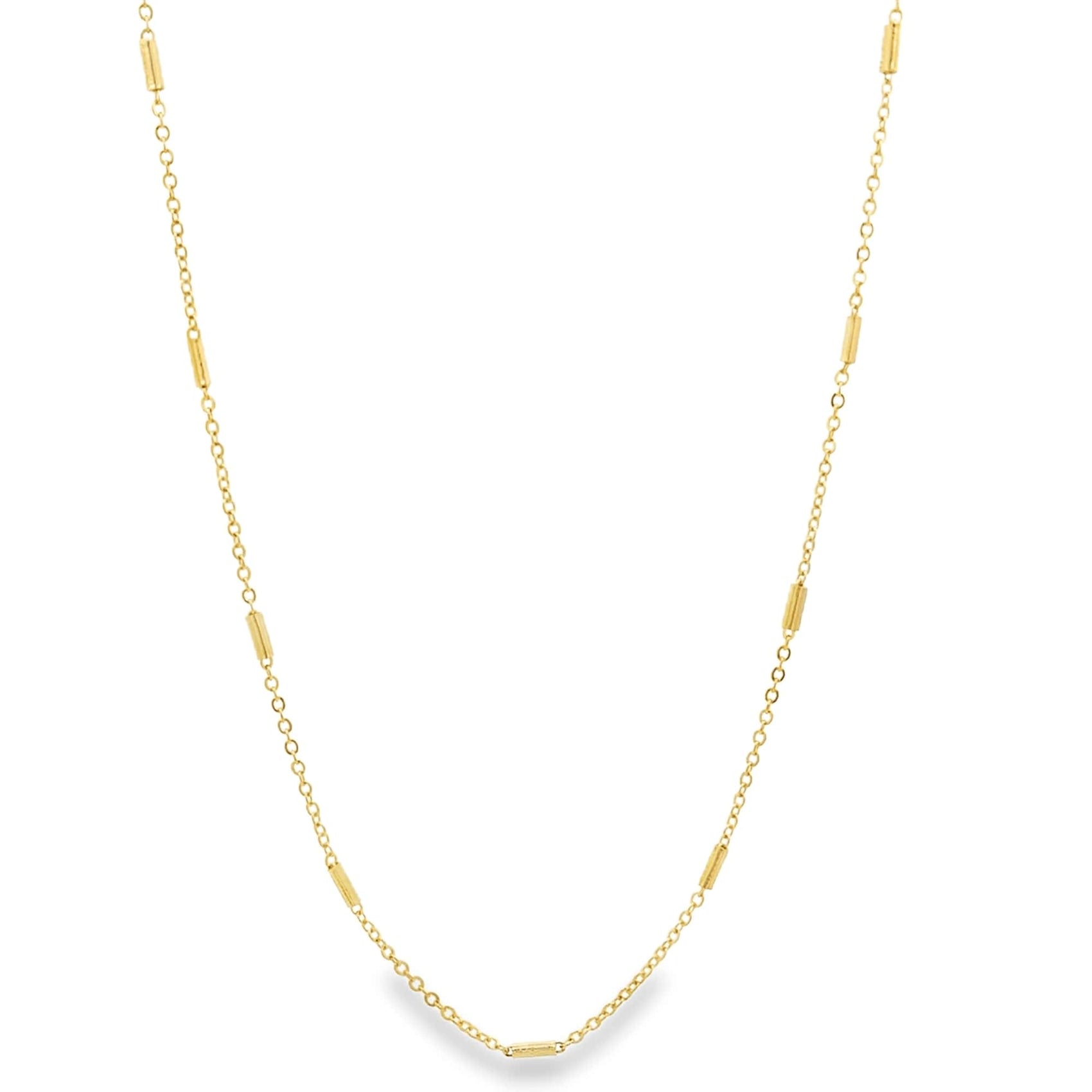 A delicate gold chain necklace drapes vertically against a clean white background, showcasing alternating link segments and small cylindrical beads.