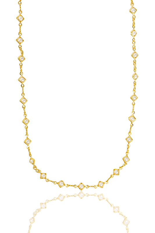 A delicate gold chain necklace features alternating square stations set with small white pearls against a clean white background.