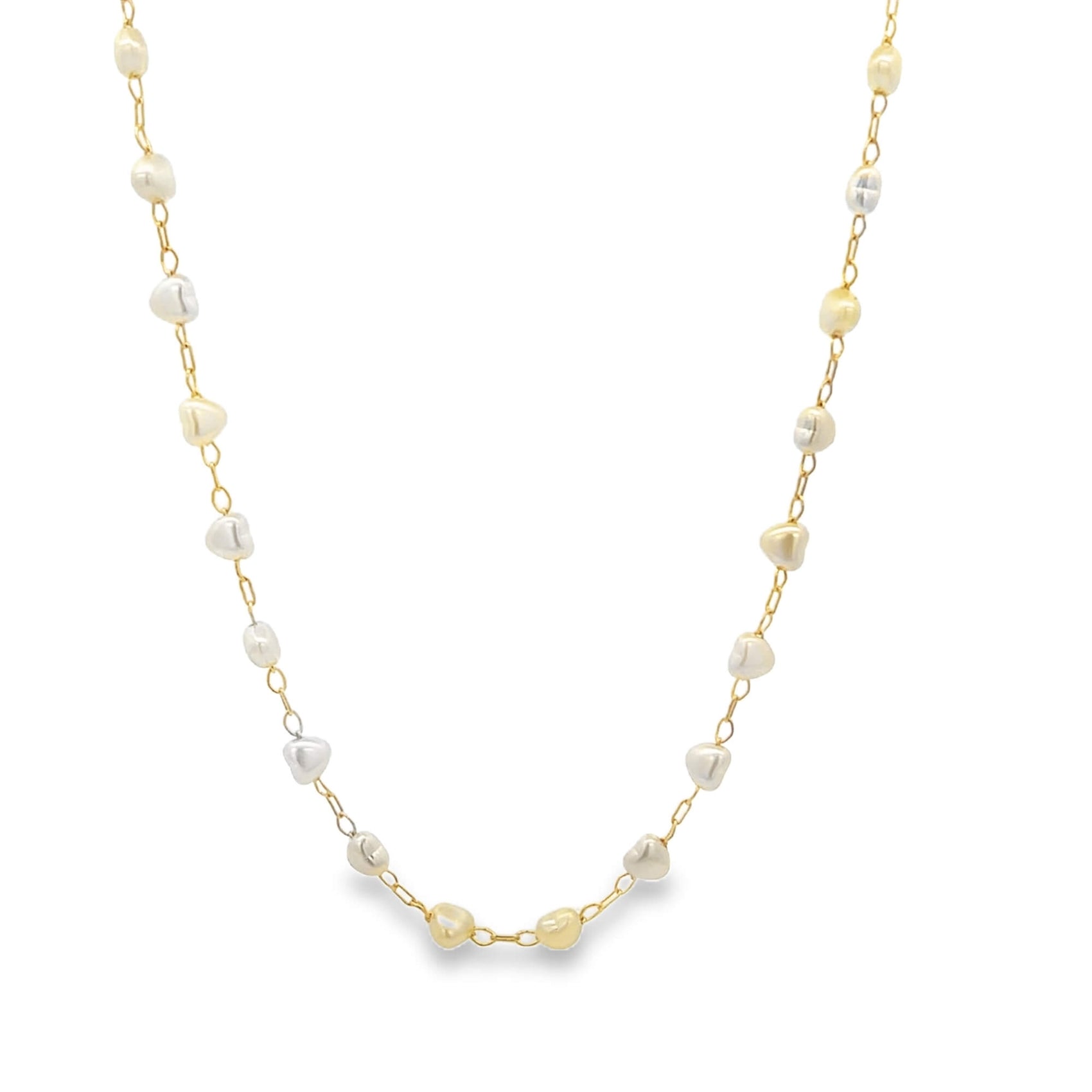 A delicate gold chain necklace drapes against a white background, featuring alternating white and yellow irregular pearl beads spaced evenly along its length.