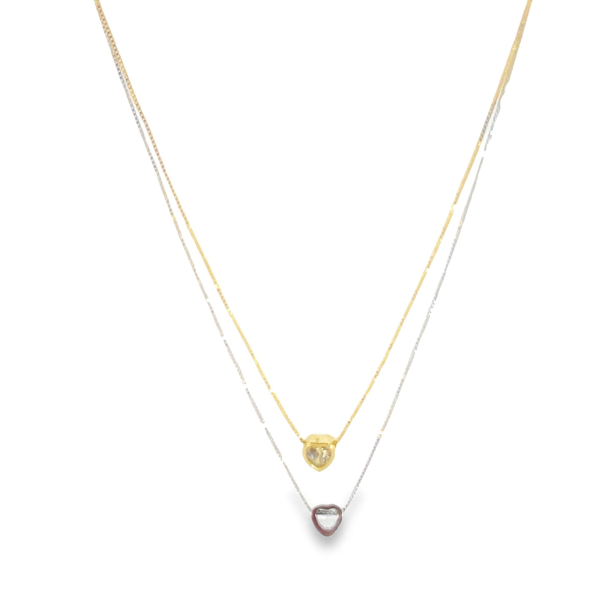 A delicate layered necklace features a gold heart pendant on the top chain and a silver heart pendant on the bottom chain.