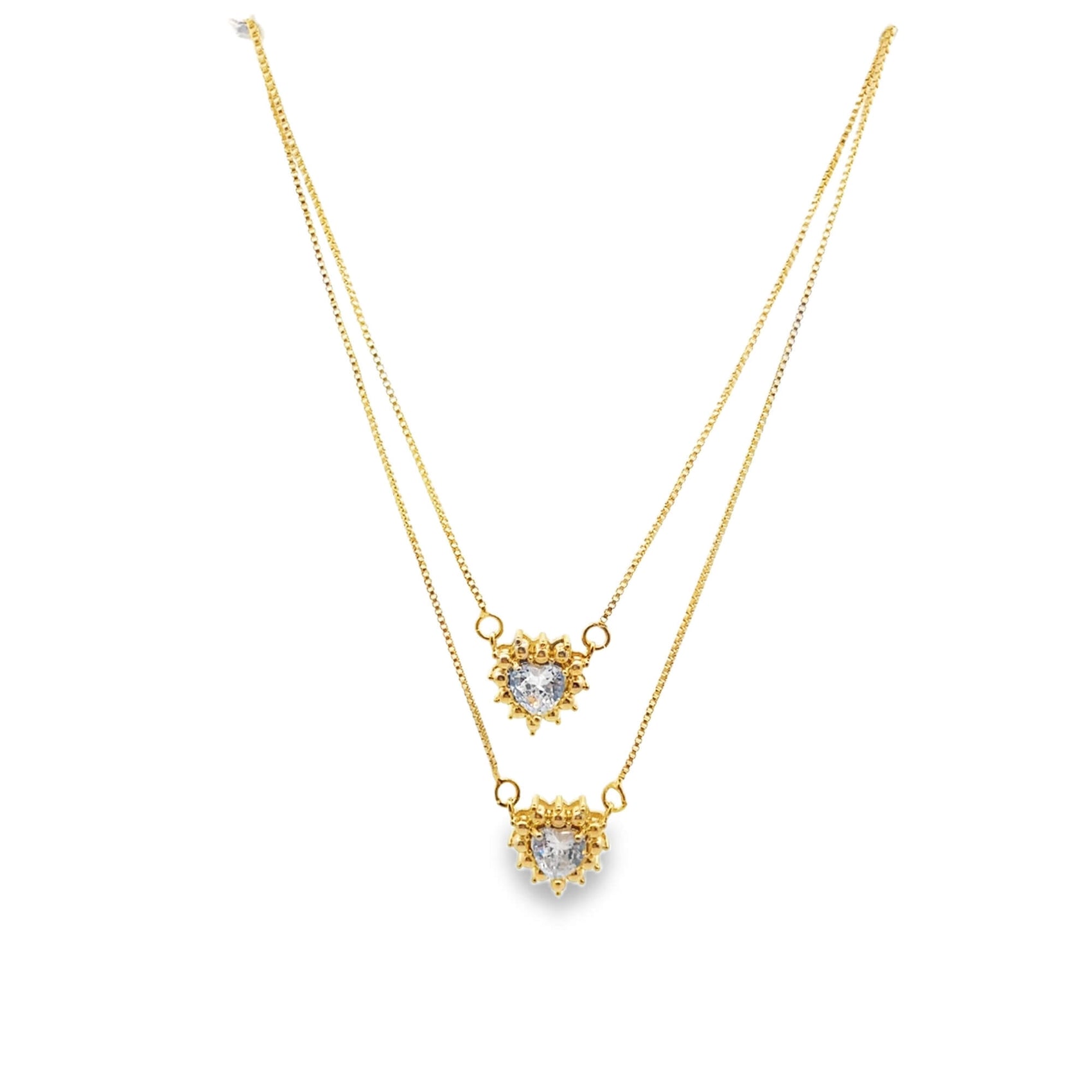 A delicate double-layered gold necklace features two sparkling heart-shaped crystal pendants against a plain white background.