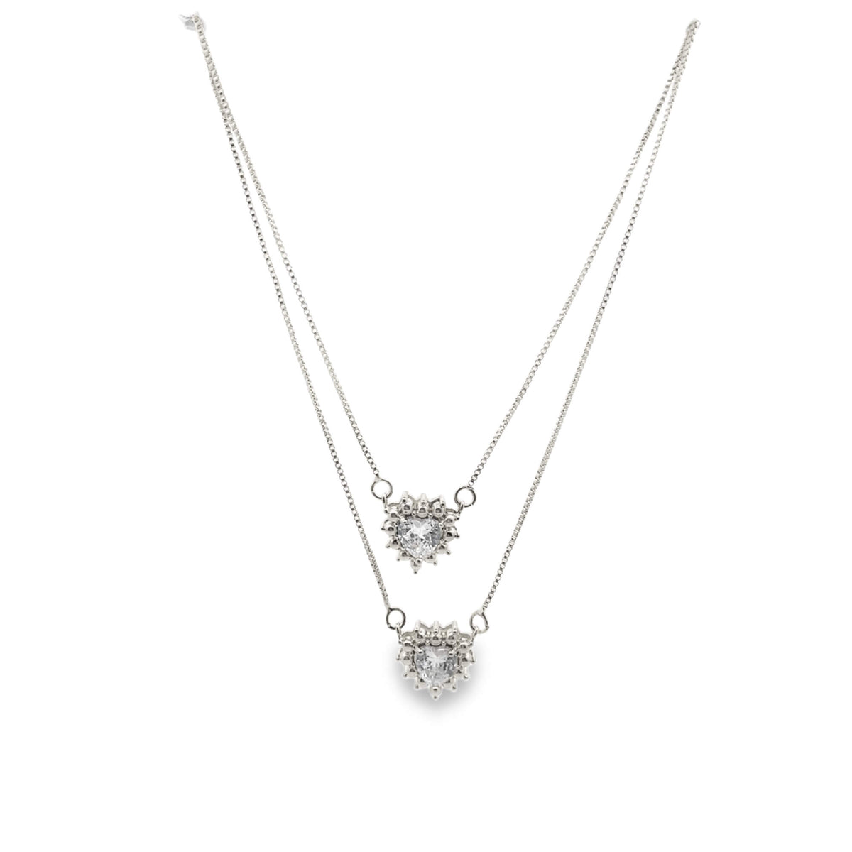 A delicate double-layered silver necklace features two sparkling heart-shaped crystal pendants against a clean white background.