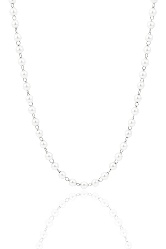 A classic white pearl necklace hangs against a clean white background, reflecting softly on a glossy surface below.