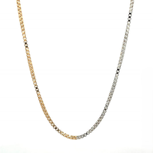 A sleek, two-tone box chain necklace gracefully drapes against a clean white background, showcasing a seamless transition from yellow gold to silver links.
