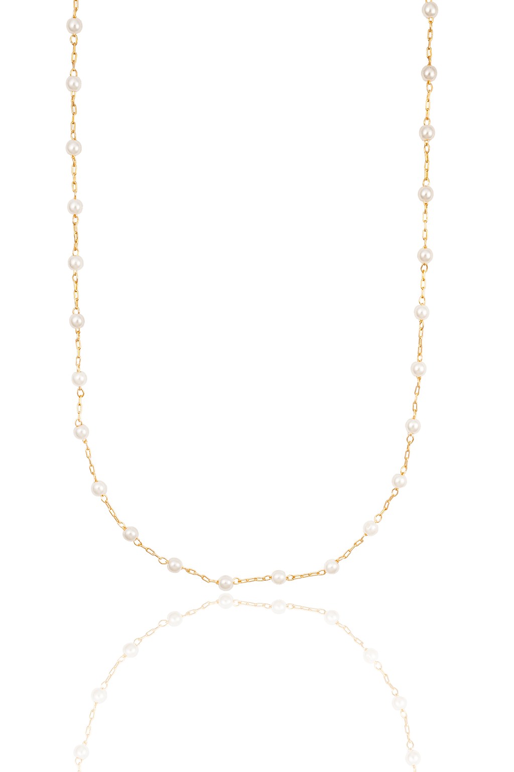 A delicate gold chain necklace featuring evenly spaced pearls hangs against a white background, casting a soft reflection below.