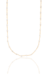 A delicate gold chain necklace featuring evenly spaced white pearls hangs against a clean white background, reflecting softly on the surface below.