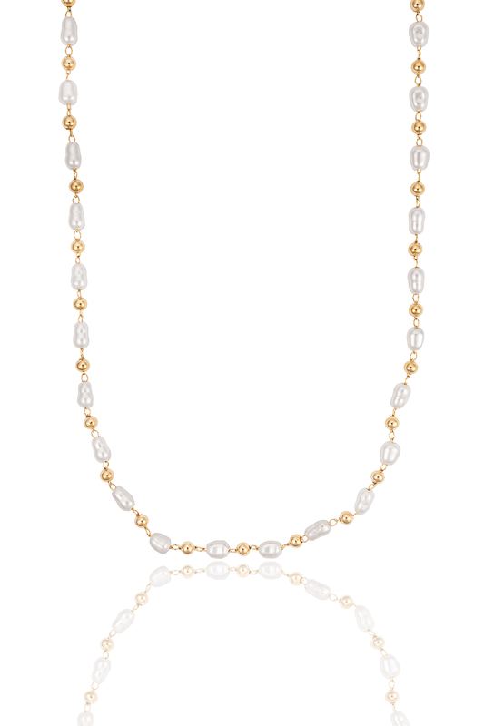 A delicate gold and baroque pearl beaded necklace drapes gracefully against a clean white background, reflecting softly on the surface below.