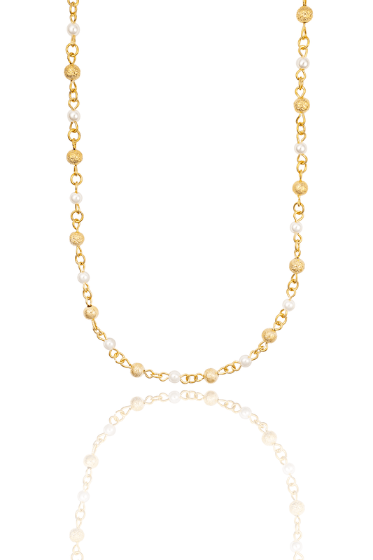A delicate gold chain necklace features alternating textured gold spheres and smooth white pearls, displayed against a clean white background with a subtle reflection.