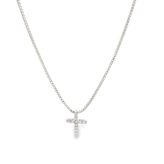 A delicate silver chain necklace features a sparkling diamond-encrusted cross pendant hanging against a plain white background.