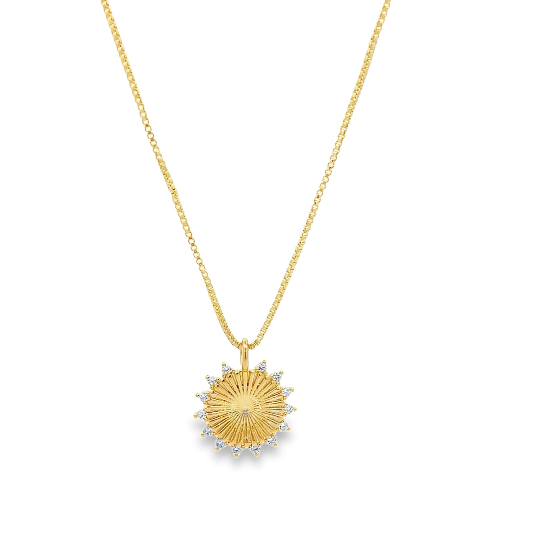 A delicate gold sunburst pendant necklace with sparkling diamond accents hangs on a fine chain against a white background.