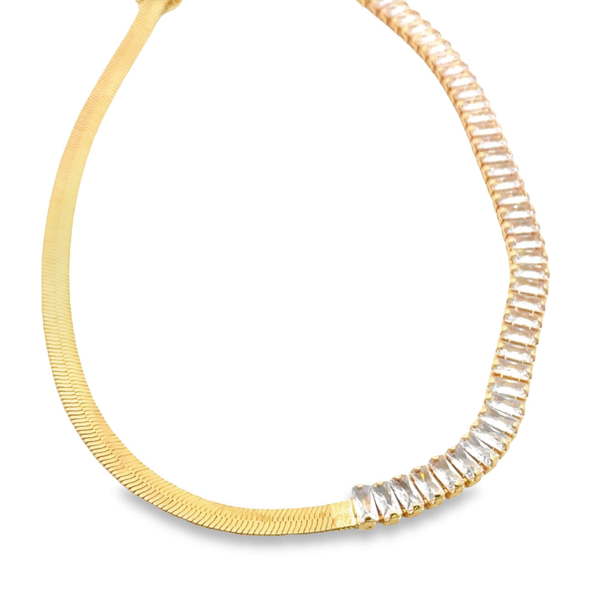 A gold herringbone chain necklace curves gracefully, featuring a sparkling row of baguette-cut zirconia stones along one side against a white background.