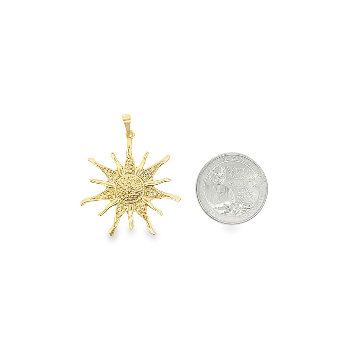 A detailed gold sunburst pendant rests next to a US quarter coin for size comparison on a white background.