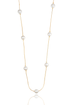 A delicate gold chain necklace with alternating white pearls dangles against a clean white background.