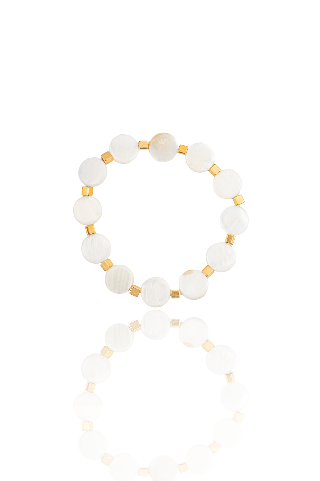A beaded bracelet made of round white mother-of-pearl stones separated by small gold square spacers rests on a reflective white surface.