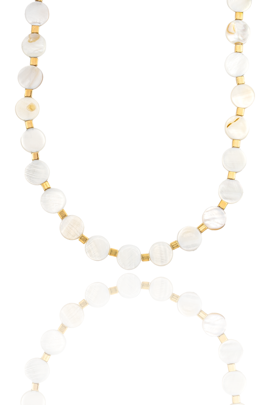 A mother-of-pearl coin bead necklace with gold spacers is displayed against a white background with a soft reflection underneath.
