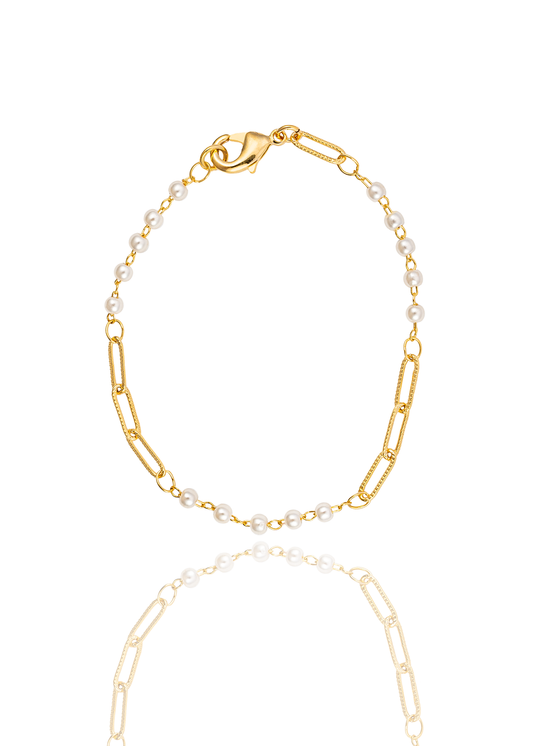 A delicate gold chain bracelet features alternating segments of small white pearls and textured paperclip links against a white background.
