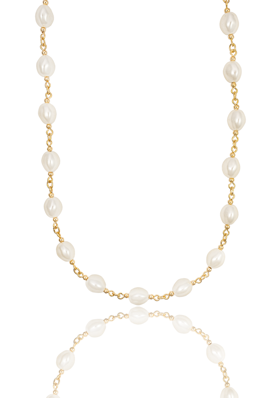 A delicate gold chain necklace with interspersed freshwater pearls rests against a clean white background with its reflection below.