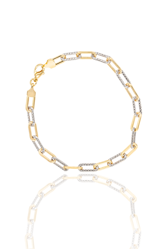 A two-tone paperclip link bracelet crafted from alternating yellow gold and textured white gold links rests on a white reflective surface.